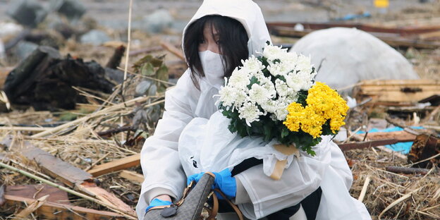 Eine Frau betet und legt Blumen nieder an der Stelle an der ihr Haus stand, das durch den Tsunami, der auch das nahegelegene Kernkraftwerk Fukushima beschädigt hat, zerstört wurde Eine Frau betet und legt Blumen nieder an der Stelle an der ihr Haus stand, das durch den Tsunami, der auch das nahegelegene Kernkraftwerk Fukushima beschädigt hat, zerstört wurde