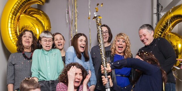 Frauen schießen mit einer Konfettikanone vor einer 666 aus Ballons Frauen schießen mit einer Konfettikanone vor einer 666 aus Ballons