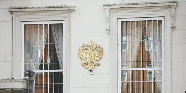 Eine Fassade mit vergitterten Fenstern und einem Wappen dazwischen Eine Fassade mit vergitterten Fenstern und einem Wappen dazwischen