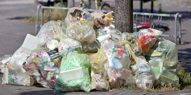 Gelbe Säcke liegen gefüllt mit Plastikmüll auf einer Straße.