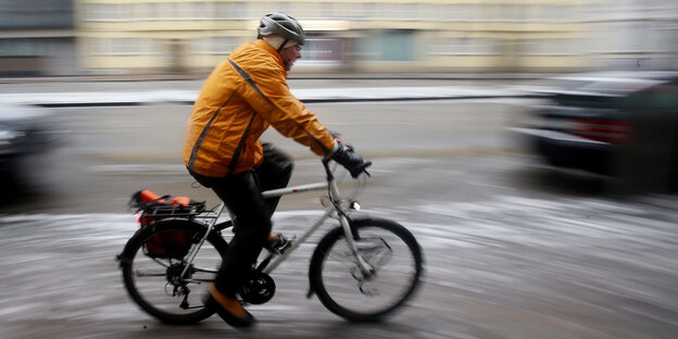 Ein Radfahrer fährt über eine zum Teil mit Schnee bedeckte Straße Ein Radfahrer fährt über eine zum Teil mit Schnee bedeckte Straße