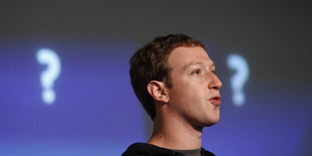 Mark Zuckerberg redet, hinter ihm sind zwei Fragezeichen an einer Wand zu sehen Mark Zuckerberg redet, hinter ihm sind zwei Fragezeichen an einer Wand zu sehen