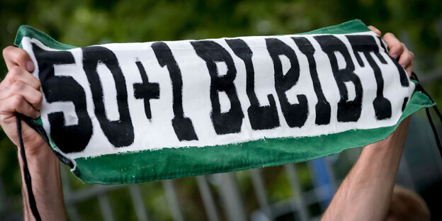 Zwei Hände halten ein Banner mit der Aufschrift "50+1 bleibt" Zwei Hände halten ein Banner mit der Aufschrift "50+1 bleibt"