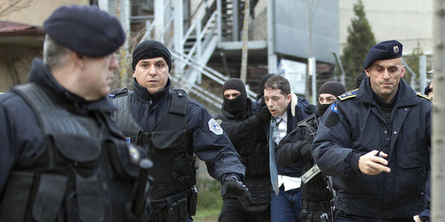 Ein Mann wird von mehreren Polizisten abgeführt Ein Mann wird von mehreren Polizisten abgeführt