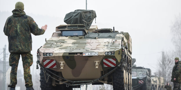 Ein Bundeswehrsoldat hält stoppend die rechte Hand vor einen Panzer Ein Bundeswehrsoldat hält stoppend die rechte Hand vor einen Panzer