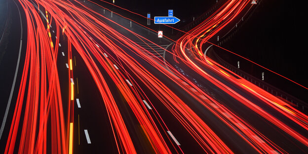 rote Lichtstreifen vor blauem Abfahrtschild