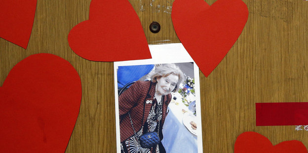 Das Foto der ermordeten Jüdin hängt von roten Papierherzen getragen, an einer Holztür