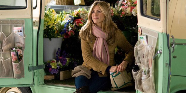 Jennifer Aniston sitzt in einem Auto, in dem viele Blumen stehen Jennifer Aniston sitzt in einem Auto, in dem viele Blumen stehen