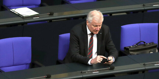Horst Seehofer sitzt in den Sitzreihen des Bundestags und tippt auf seinem Smartphone Horst Seehofer sitzt in den Sitzreihen des Bundestags und tippt auf seinem Smartphone