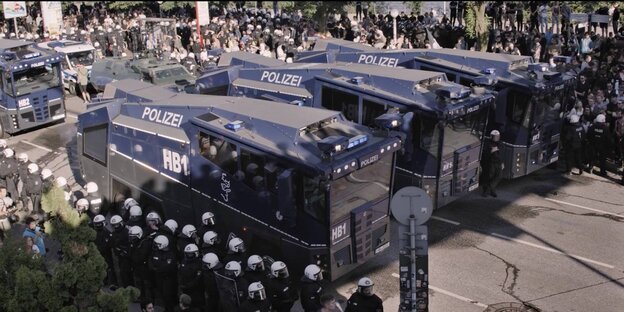 Behelmte Polizisten und Polizei-Räumfahrzeuge füllen eine Straße aus. Behelmte Polizisten und Polizei-Räumfahrzeuge füllen eine Straße aus.