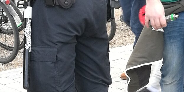 Ein Polizist hat am Gürtel einen Schlagstock mit einem Aufkleber "Spaß kostet" hängen. Ein Polizist hat am Gürtel einen Schlagstock mit einem Aufkleber "Spaß kostet" hängen.