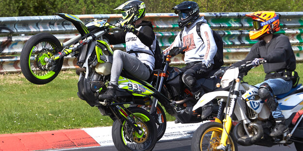 Ein Motorradfahrer fährt beim Korso zum Saisonauftakt unter dem Motto "Anlassen" auf dem Nürburgring auf dem Hinterrad. Ein Motorradfahrer fährt beim Korso zum Saisonauftakt unter dem Motto "Anlassen" auf dem Nürburgring auf dem Hinterrad.