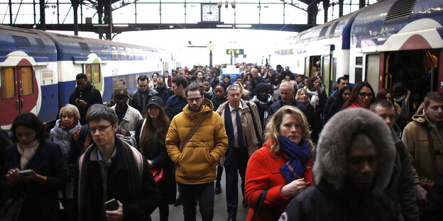 Menschen hasten aus einem Bahnhof