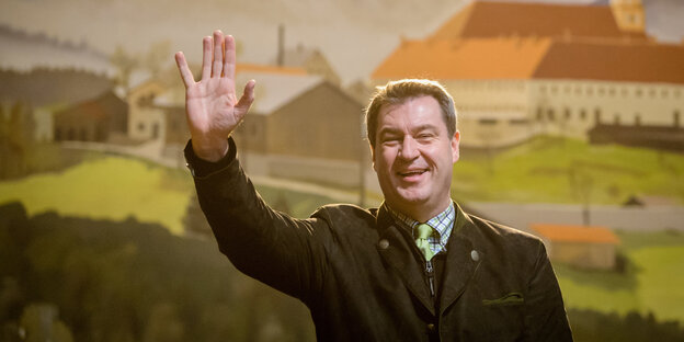 Söder winkt, im Hintergrund gemalte Berge Söder winkt, im Hintergrund gemalte Berge