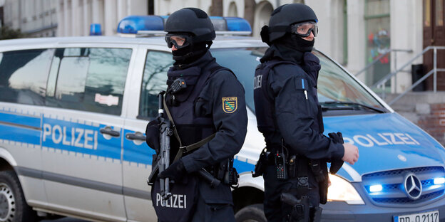 Zwei Polizisten stehen neben einem Polizeiauto Zwei Polizisten stehen neben einem Polizeiauto