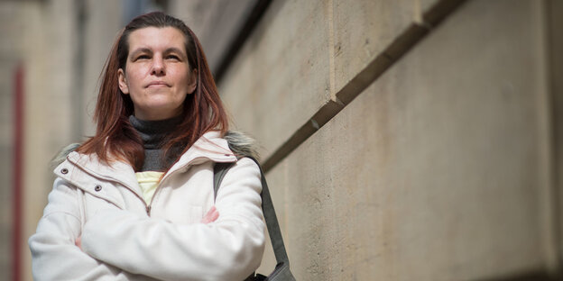 Eine Frau steht an einer Mauer Eine Frau steht an einer Mauer