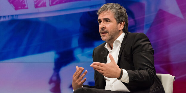 Deniz Yücel sitzt auf einem Sessel und gestikuliert Deniz Yücel sitzt auf einem Sessel und gestikuliert