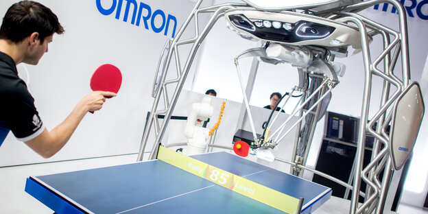 Ein Mensch spielt Tischtennis gegen einen Roboter. Ein Mensch spielt Tischtennis gegen einen Roboter.