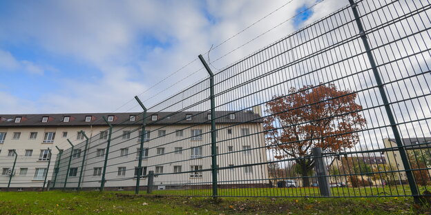 Gebäude, die von einem stacheldrahtbewehrten Zaun umgeben sind