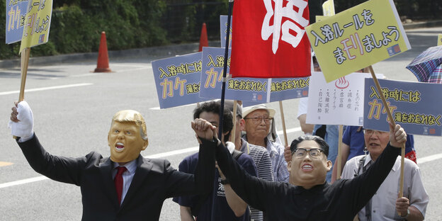 Demonstrant*innen in Tokyo tragen Masken von Donald Trump und Kim Jong Un Demonstrant*innen in Tokyo tragen Masken von Donald Trump und Kim Jong Un