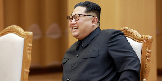 Kim Jong Un sitzt auf einem Stuhl und lacht Kim Jong Un sitzt auf einem Stuhl und lacht