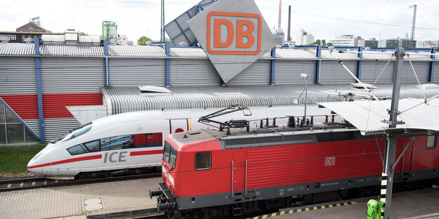 Ein ICE und eine Lokomotive vor einem Emblem der Deutschen Bahn Ein ICE und eine Lokomotive vor einem Emblem der Deutschen Bahn