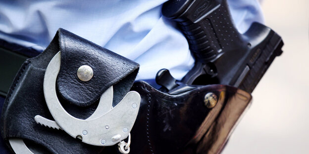 Das Halfter eines Polizisten, in dem eine Pistole und Handschellen zu sehen sind Das Halfter eines Polizisten, in dem eine Pistole und Handschellen zu sehen sind