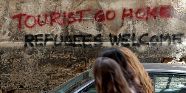 Graffiti "Tourist go home" an einer Wand