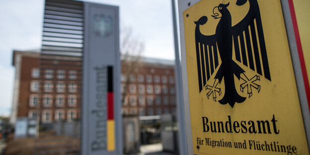 Ein gelbes Schild mit einem Bundesadler an einem Tor Ein gelbes Schild mit einem Bundesadler an einem Tor