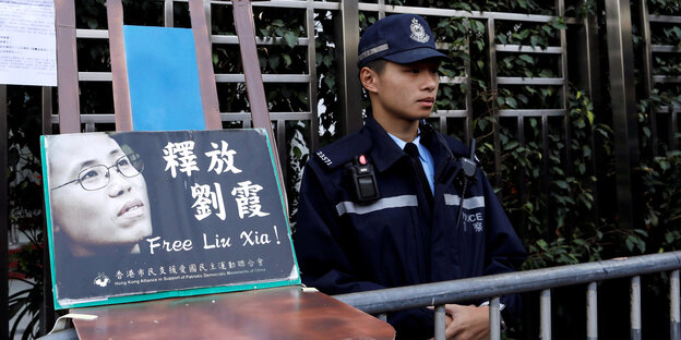 Polizist neben Stuhl mit Foto von Liu Xia Polizist neben Stuhl mit Foto von Liu Xia