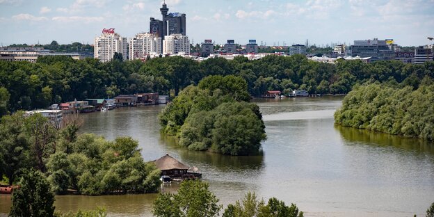 Über eine Flusslandschaft hinweg ist ein Hochhauskomplex sichtbar Über eine Flusslandschaft hinweg ist ein Hochhauskomplex sichtbar