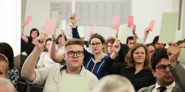 Besucher der Veranstaltung mit Stimmzetteln.