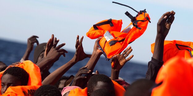 Flüchtlinge auf einem Boot fangen Rettungswesten Flüchtlinge auf einem Boot fangen Rettungswesten
