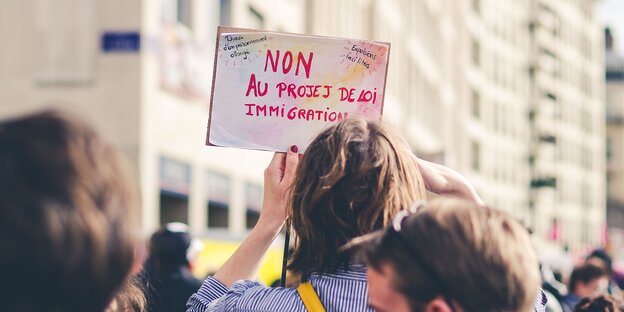 Eine Frau hält ein französisches Plakat auf einer Demo gegen leichtere Abschiebung hoch Eine Frau hält ein französisches Plakat auf einer Demo gegen leichtere Abschiebung hoch