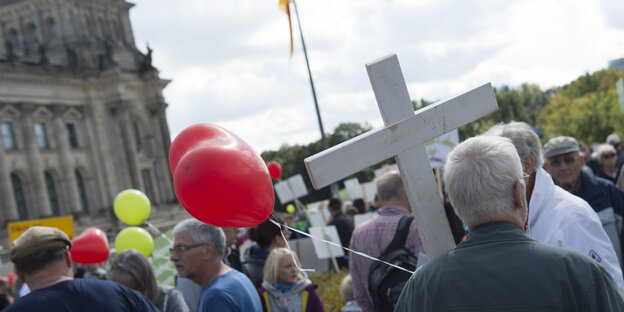 Menschen vor dem Reichstag, einer hält ein weißes Kreuz