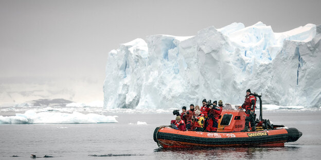 Menschen in einem Greenpeace-Boot. Im Hintergrund sieht man Eisberge Menschen in einem Greenpeace-Boot. Im Hintergrund sieht man Eisberge