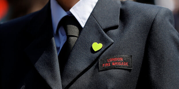 Eine Uniform in Nahaufnahme. Darauf steht „London Fire Brigade“. Eine Uniform in Nahaufnahme. Darauf steht „London Fire Brigade“.