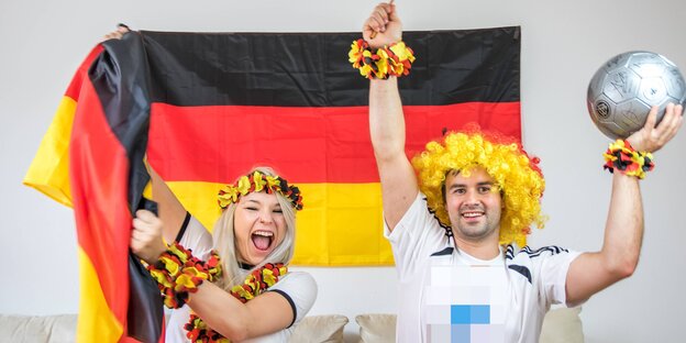Zwei Menschen jubeln mit Fanartikeln in Deutschlandfarben Zwei Menschen jubeln mit Fanartikeln in Deutschlandfarben