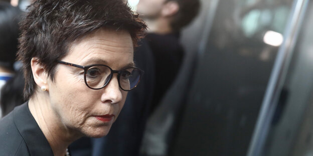 Eine Frau mit kurzen dunklen Haaren und Brille mit schwarzem Rahmen Eine Frau mit kurzen dunklen Haaren und Brille mit schwarzem Rahmen