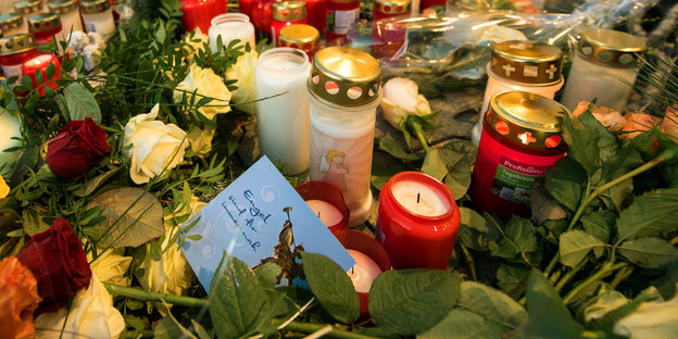 Kerzen und Blumen, dazwischen eine Kondolenzkarte Kerzen und Blumen, dazwischen eine Kondolenzkarte