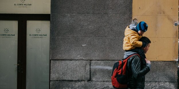 Ein Mann trägt ein Kind auf seinen Schultern Ein Mann trägt ein Kind auf seinen Schultern