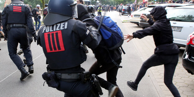 Ein Polizist schlägt mit seinem Knüppel einen G20-Gegner.