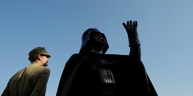 Lord Darth Vader als Standdenkmal, ein Mann steht daneben und sieht zu Darth Vader auf Lord Darth Vader als Standdenkmal, ein Mann steht daneben und sieht zu Darth Vader auf