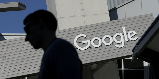 Die Silouette eines Menschen vor einem Gebäude, auf dem das Logo von Google zu sehen ist Die Silouette eines Menschen vor einem Gebäude, auf dem das Logo von Google zu sehen ist