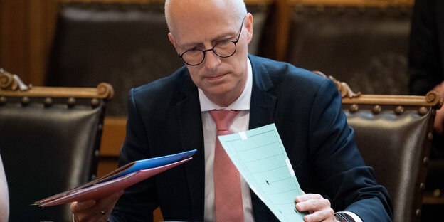 Peter Tschentscher klappt eine Akte auf und liest darin Peter Tschentscher klappt eine Akte auf und liest darin