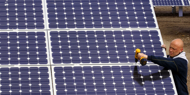 Ein Mann montiert Solarmodule auf einer Photovoltaikanlage Ein Mann montiert Solarmodule auf einer Photovoltaikanlage