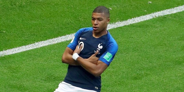 Kylian Mbappé feiert kniend und mit verschränkten Armen ein Tor auf dem Rasen Kylian Mbappé feiert kniend und mit verschränkten Armen ein Tor auf dem Rasen
