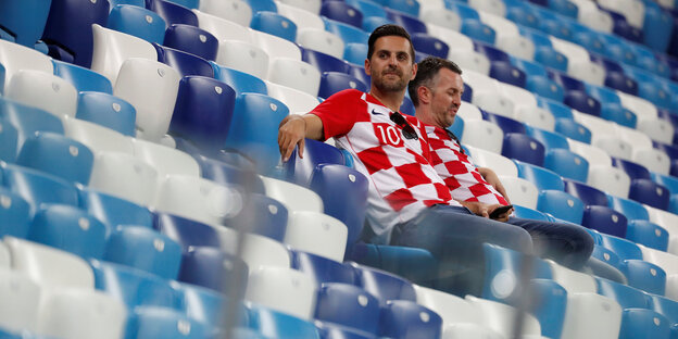 Zwei Kroatische Fans sitzen alleine in den Rängen eines Stadions. Zwei Kroatische Fans sitzen alleine in den Rängen eines Stadions.