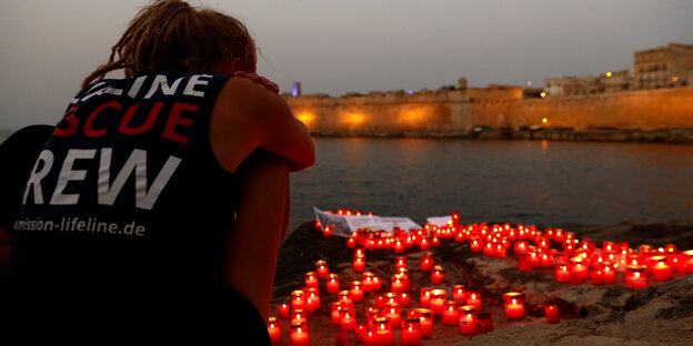 Ein Crew-Mitglied der Lifeline mit Gedenkkerzen am Strand von Malta Ein Crew-Mitglied der Lifeline mit Gedenkkerzen am Strand von Malta