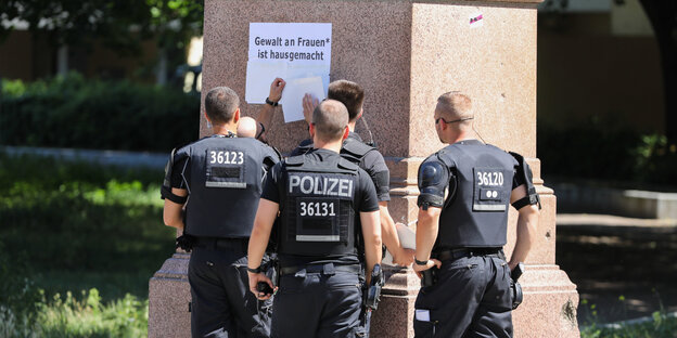 Polizisten überkleben Schrift an einer Säule Polizisten überkleben Schrift an einer Säule